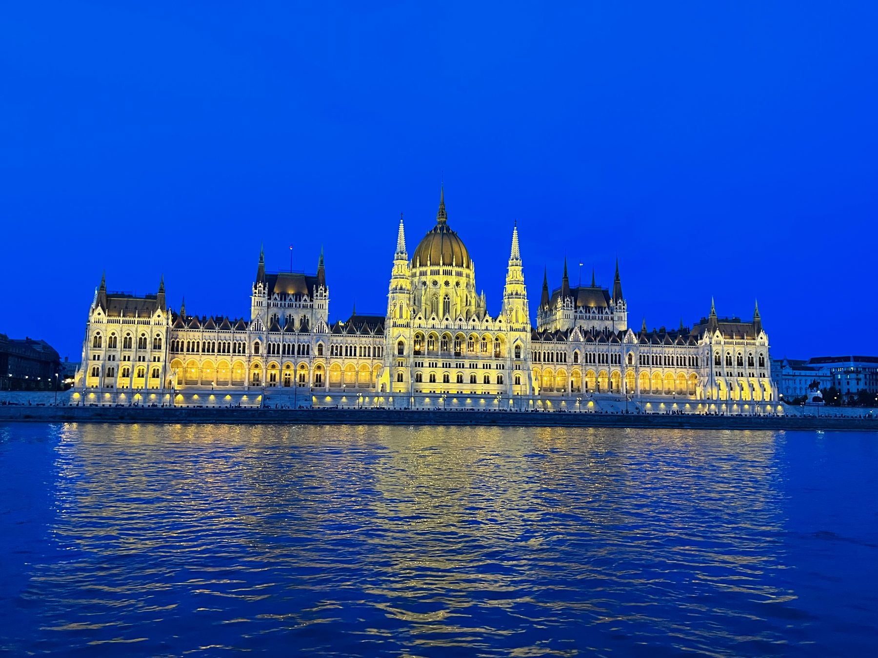 Hungarian Parliament lit gold at blue hour, from the Danube